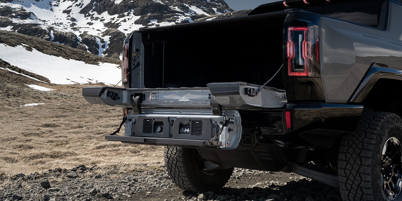 Close-up of the 2026 GMC HUMMER EV Pickup Truck's Multipro Tailgate Open While Parked near Snowy Mountain