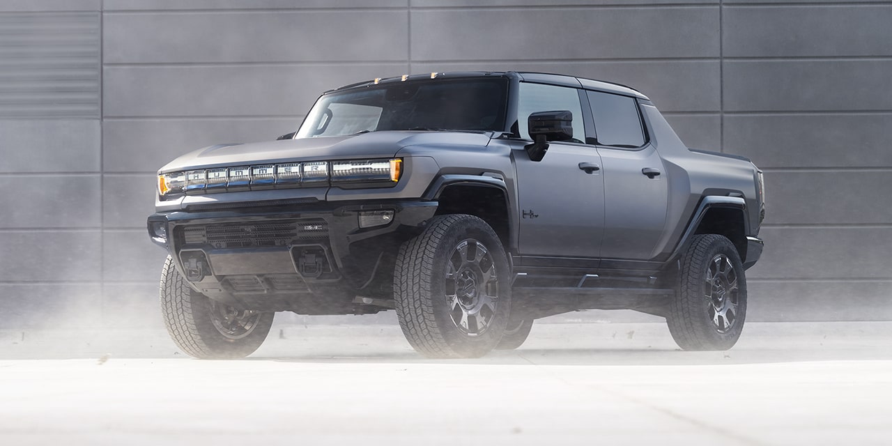 Front Three-Quarters View of the GMC HUMMER EV Pickup Truck Parked by a Concrete Wall Surrounded by Fog