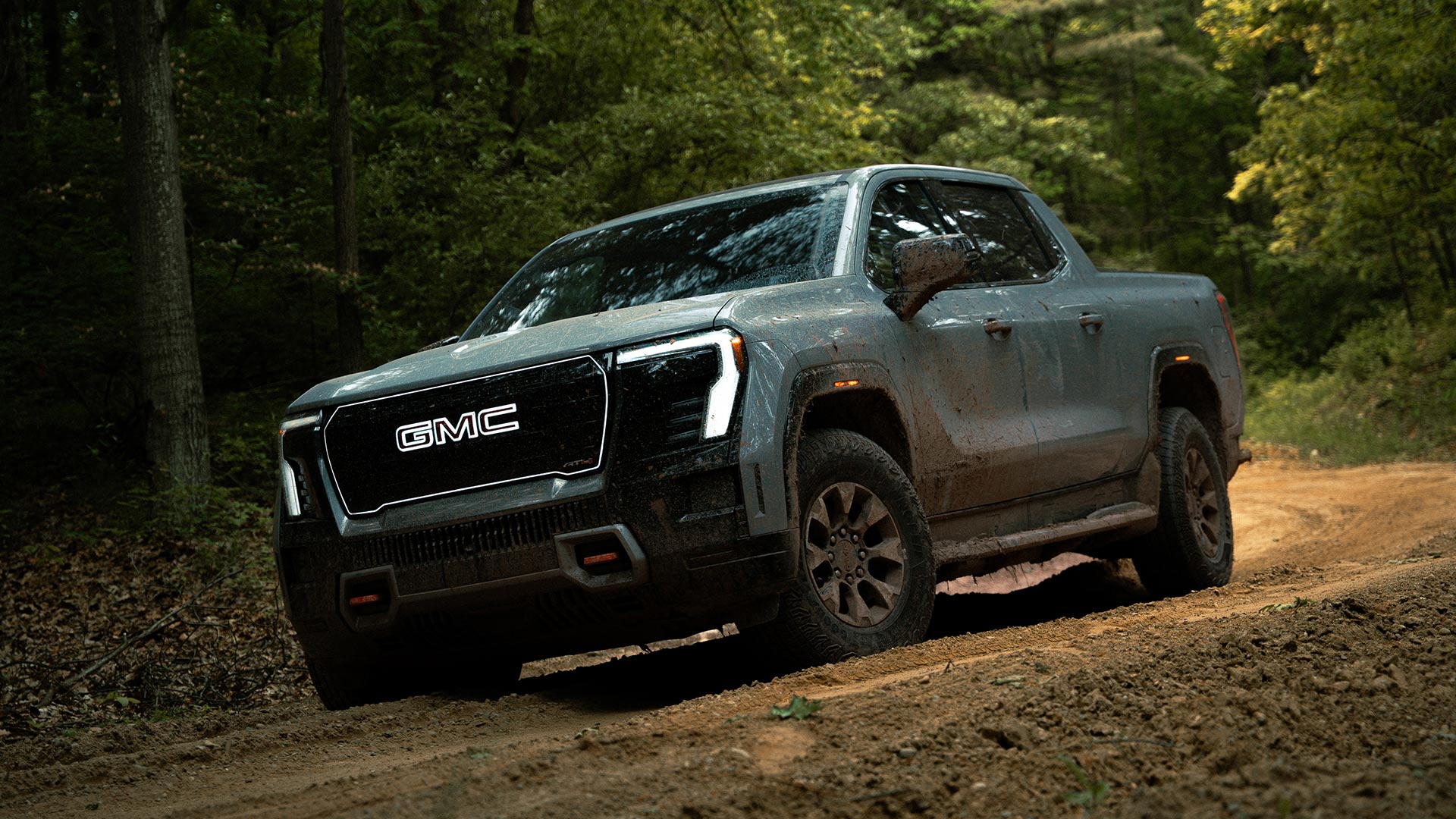 Front View of the 2026 GMC Sierra EV AT4 Pickup Truck Driving Through the Forest Off-Road