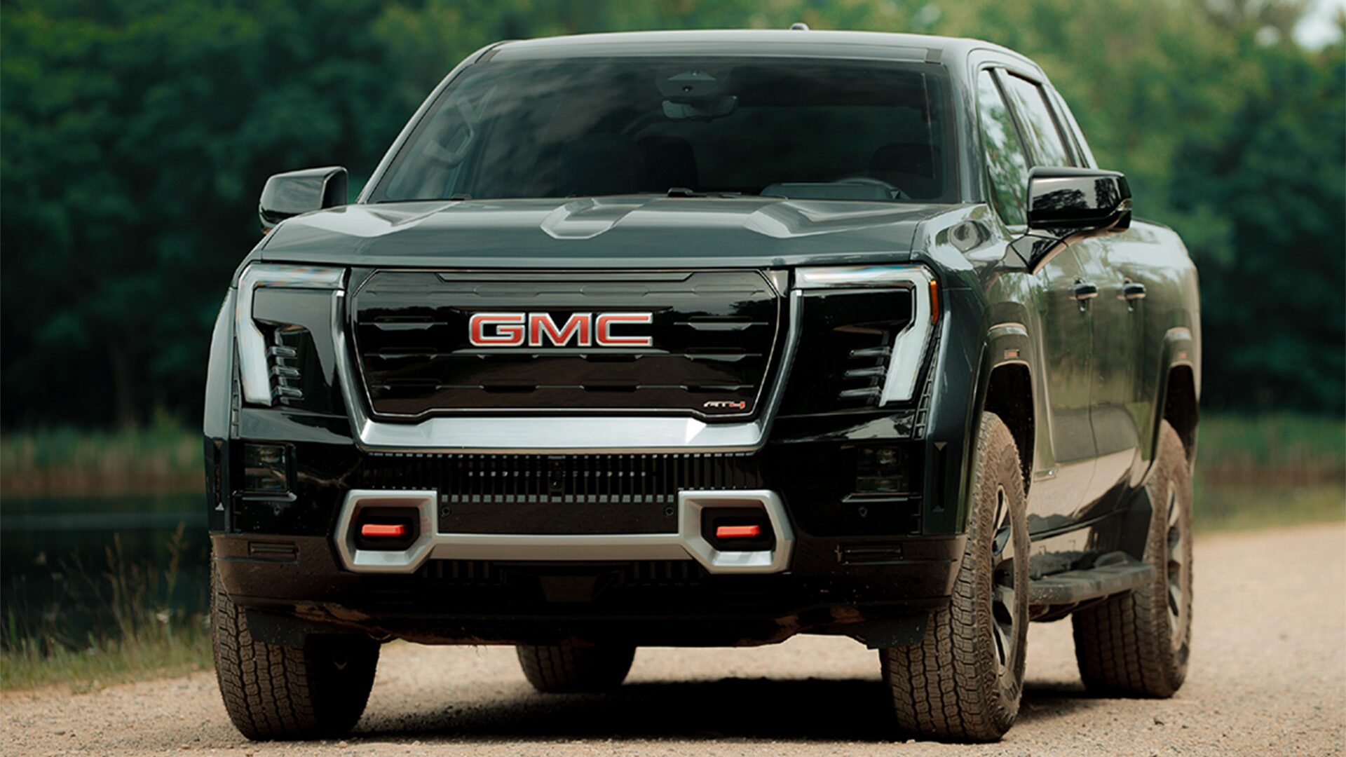 The 2026 GMC Sierra EV AT4 Pickup Truck Pulling a Boat Along a Road on the Coast