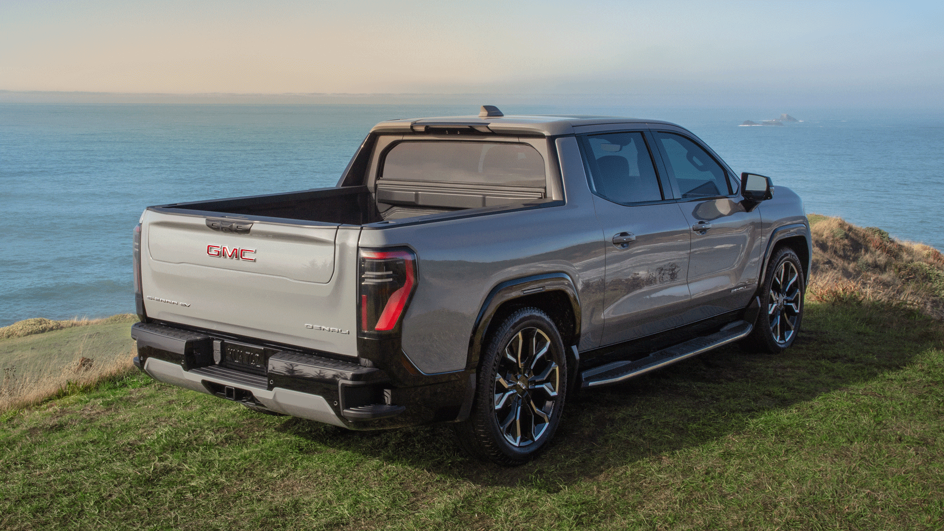 The 2026 GMC Sierra EV Charging Through a Portable Charger in the Bed and the Multipro Tailgate Being Utilized