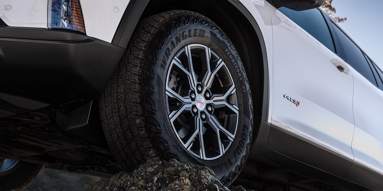 Close-up View of the 2026 GMC Acadia AT4 Mid-Size Off-Road SUV Driving over Rough Terrain