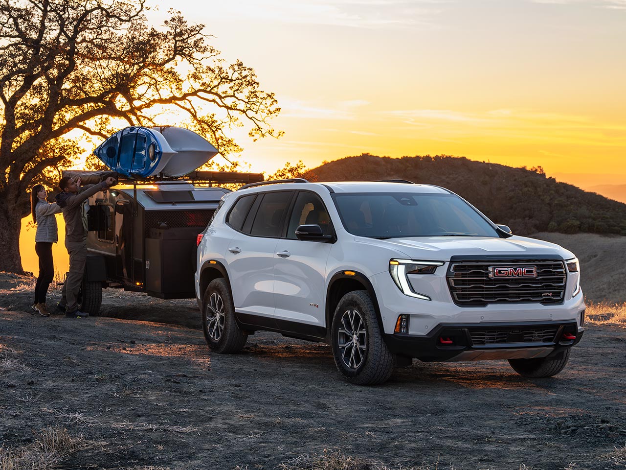 The 2026 GMC Acadia Mid-Size SUV Towing a Trailer over Rough Terrain