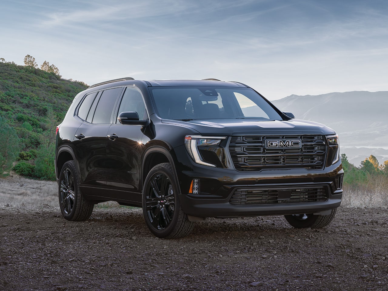 Front Three-Quarters View of the 2026 GMC Acadia Elevation Mid-Size SUV Driving Down the Open Road