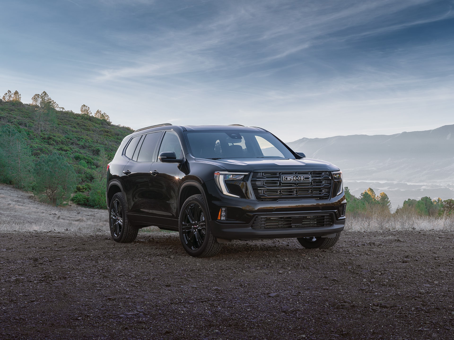 A Front Angled View of the 2026 GMC Acadia Elevation Parked Outside with Mountains in the Background