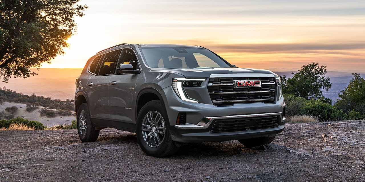 Front Three-Quarters View of the 2026 GMC Acadia Elevation Mid-Size SUV with a Sunset View in the Distance