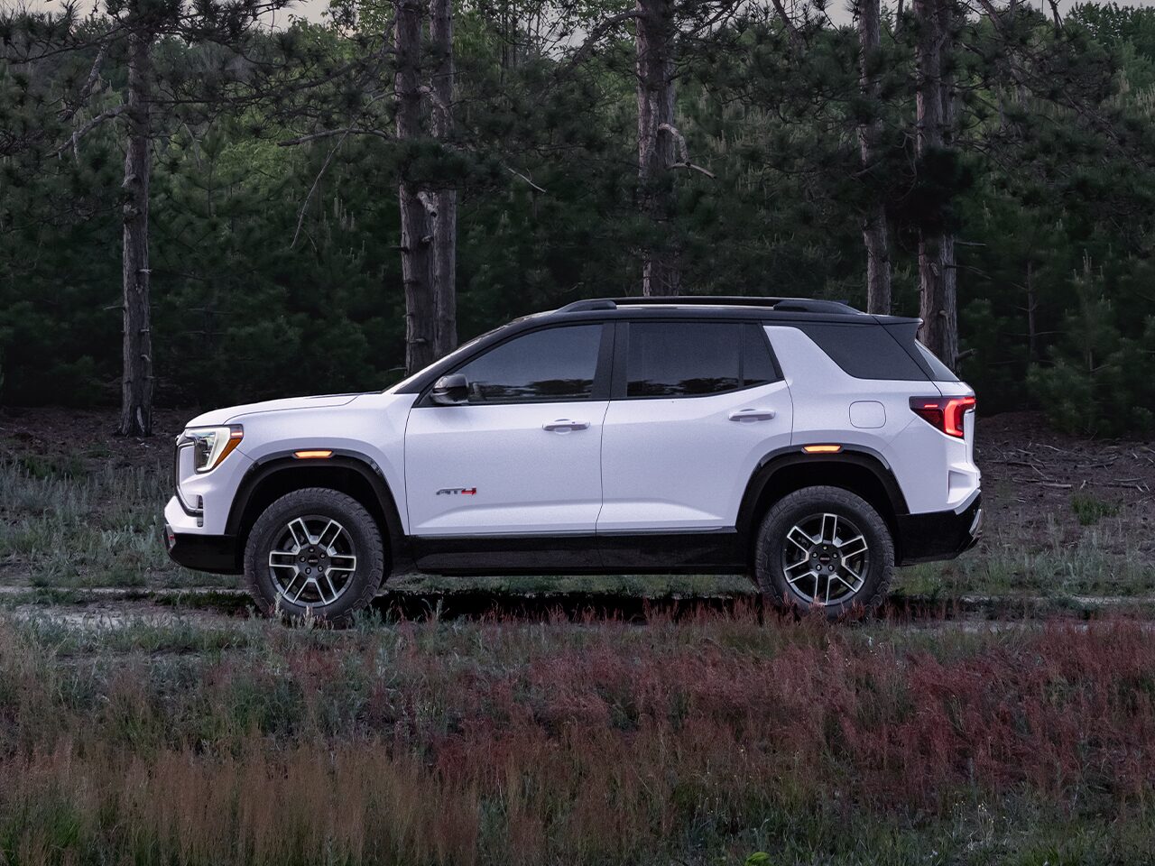 Profile View of the 2026 GMC Terrain AT4 Small Off-Road SUV Driving Through the Forest