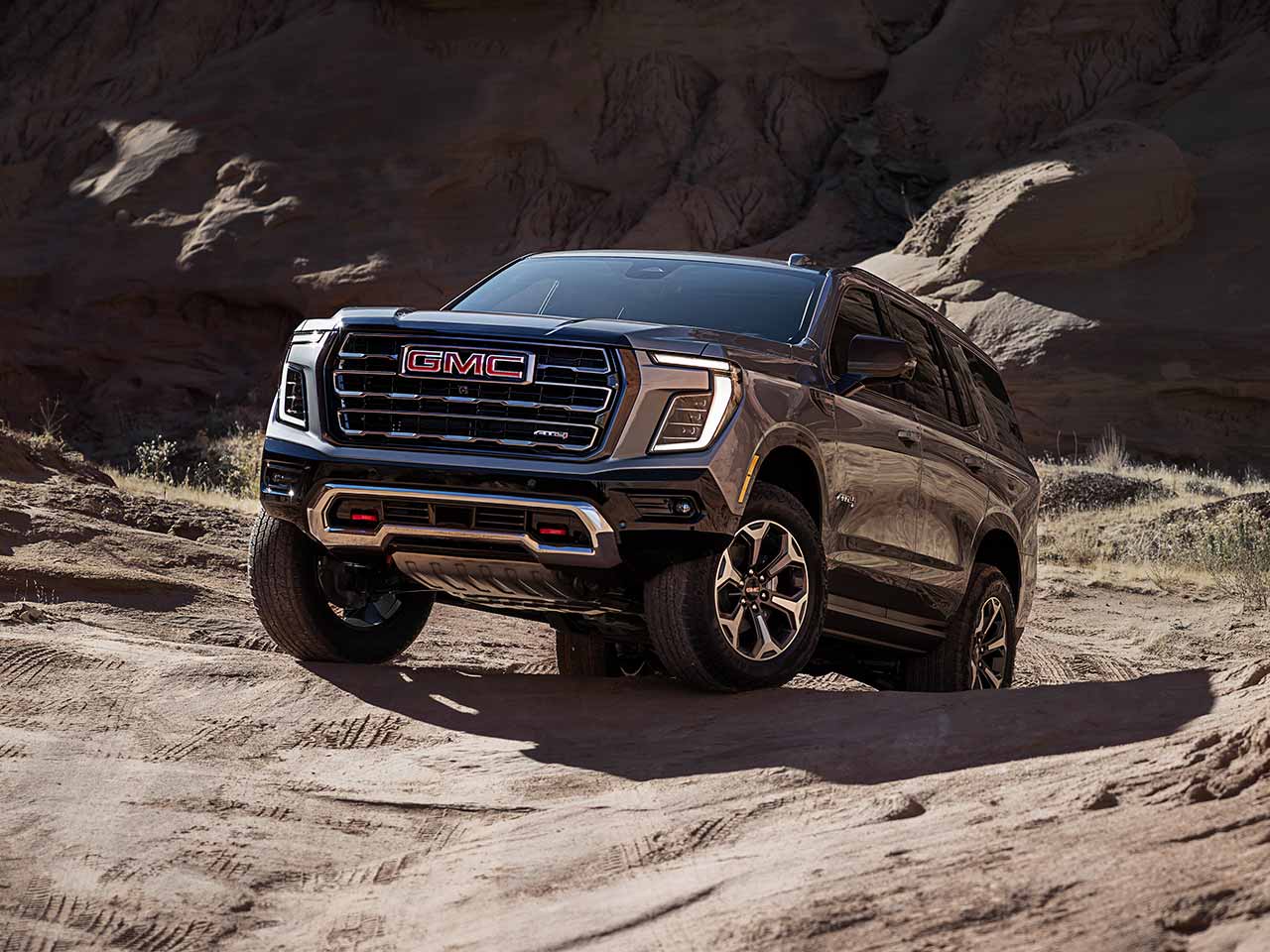 The 2026 GMC Yukon AT4 Full-Size Off-Road SUV Driving Over Rough Terrain Through a Desert