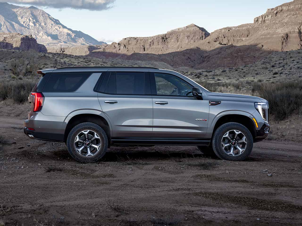 Profile View of the 2026 GMC Yukon AT4 Full-Size Off-Road SUV Parked in the Desert with Mountains in the Distance