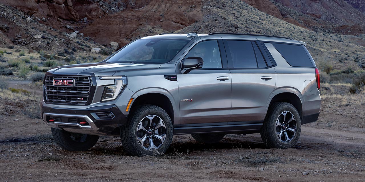 Front Three-Quarter View of the 2026 GMC Yukon AT4 Full-Size Off-Road SUV Parked Next to a Beautiful Mountain Range
