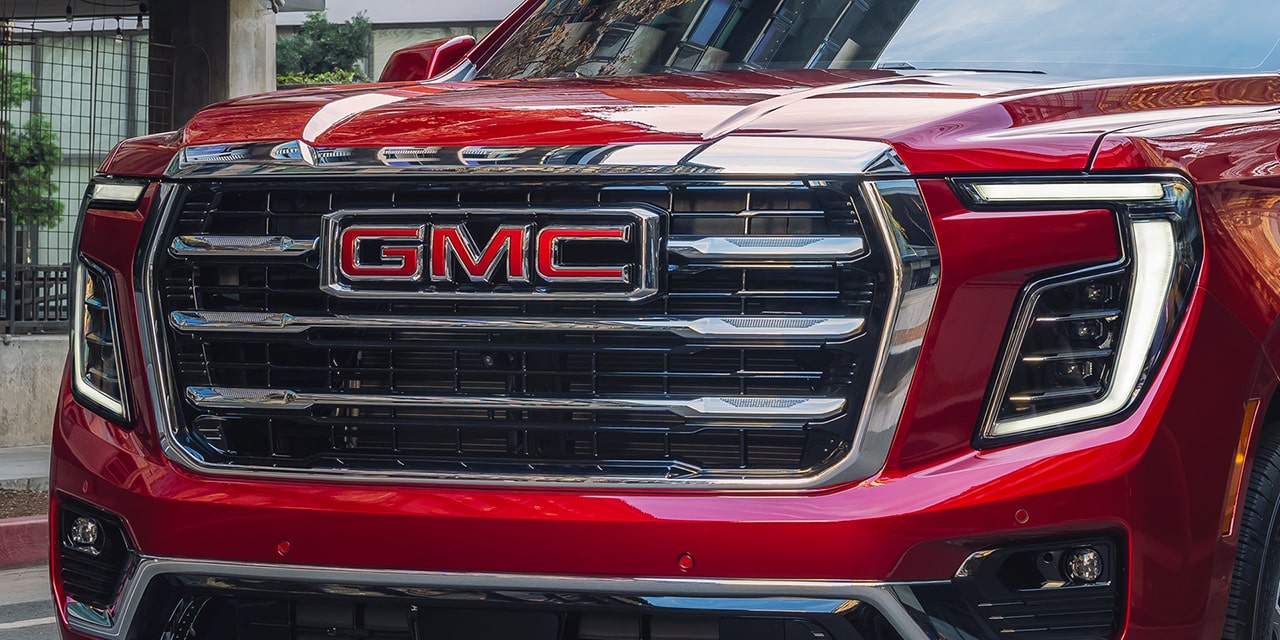 Front Three-Quarter View of the 2026 GMC Yukon Elevation Full-Size SUV Driving Down a City Street