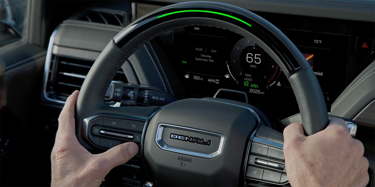 Close-up of the Driver Holding the Steering Wheel as They Press the Super Cruise Control Button on Their Steering Wheel