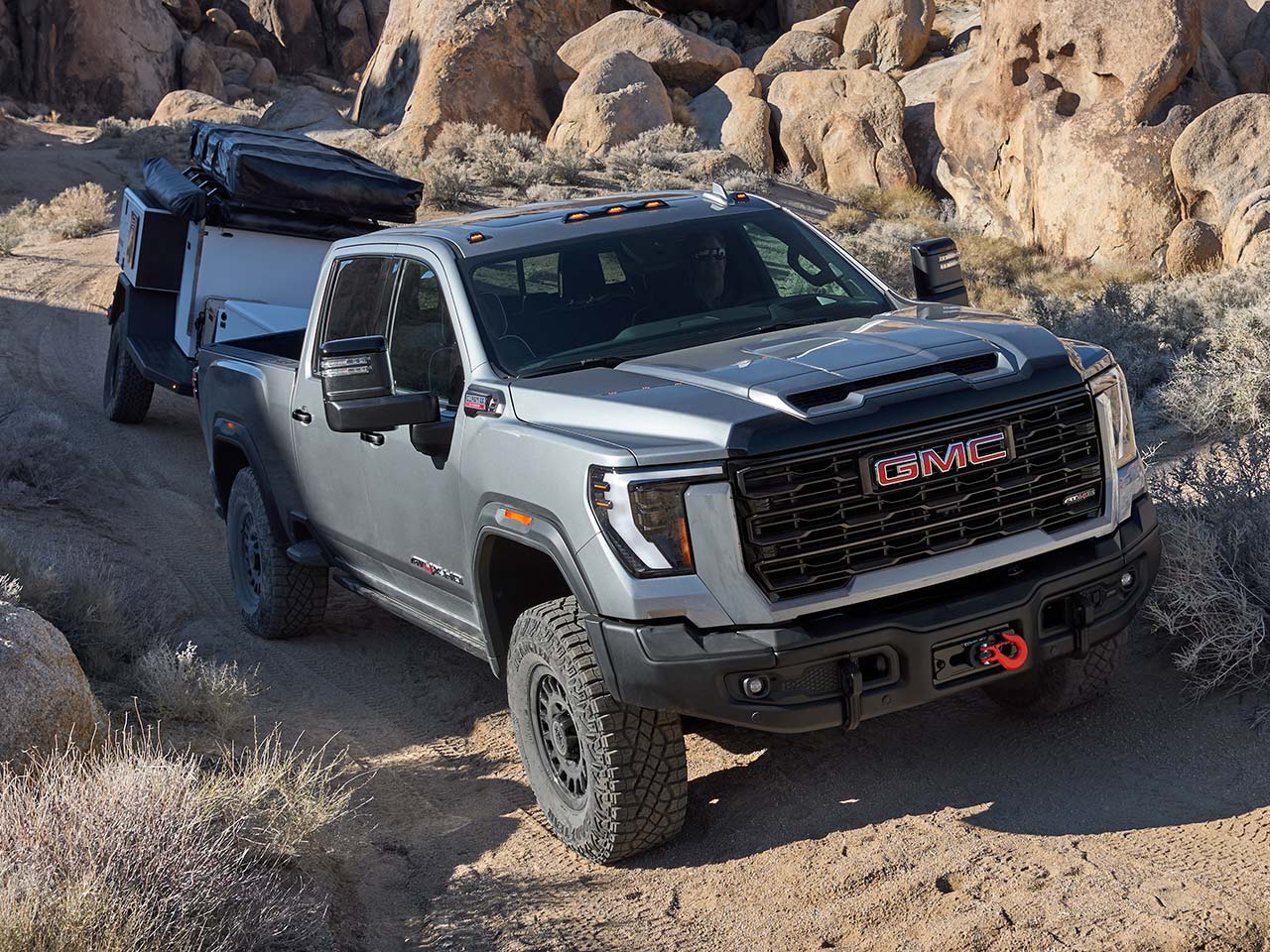 The 2026 GMC Sierra HD AT4X AEV Heavy Duty Off-Road Truck Hauling a Trailer Through a Dirt Road