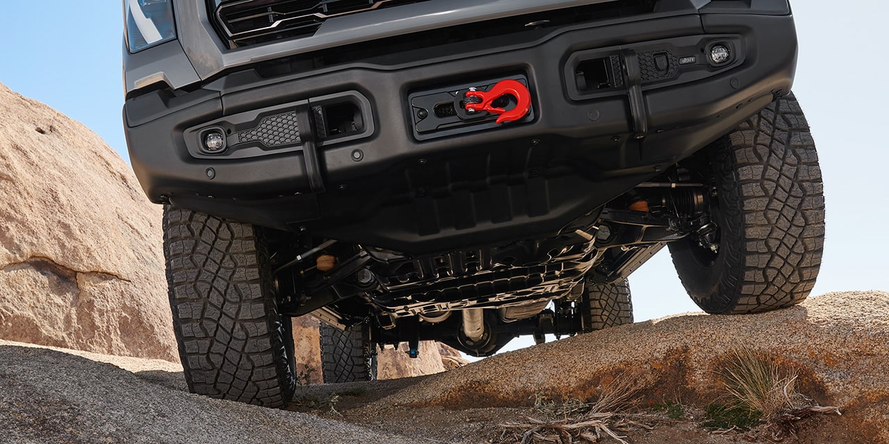 Close-up of the Front End on a 2026 GMC Sierra HD AT4X Heavy Duty Off-Road Truck Driving on Rocky Terrain