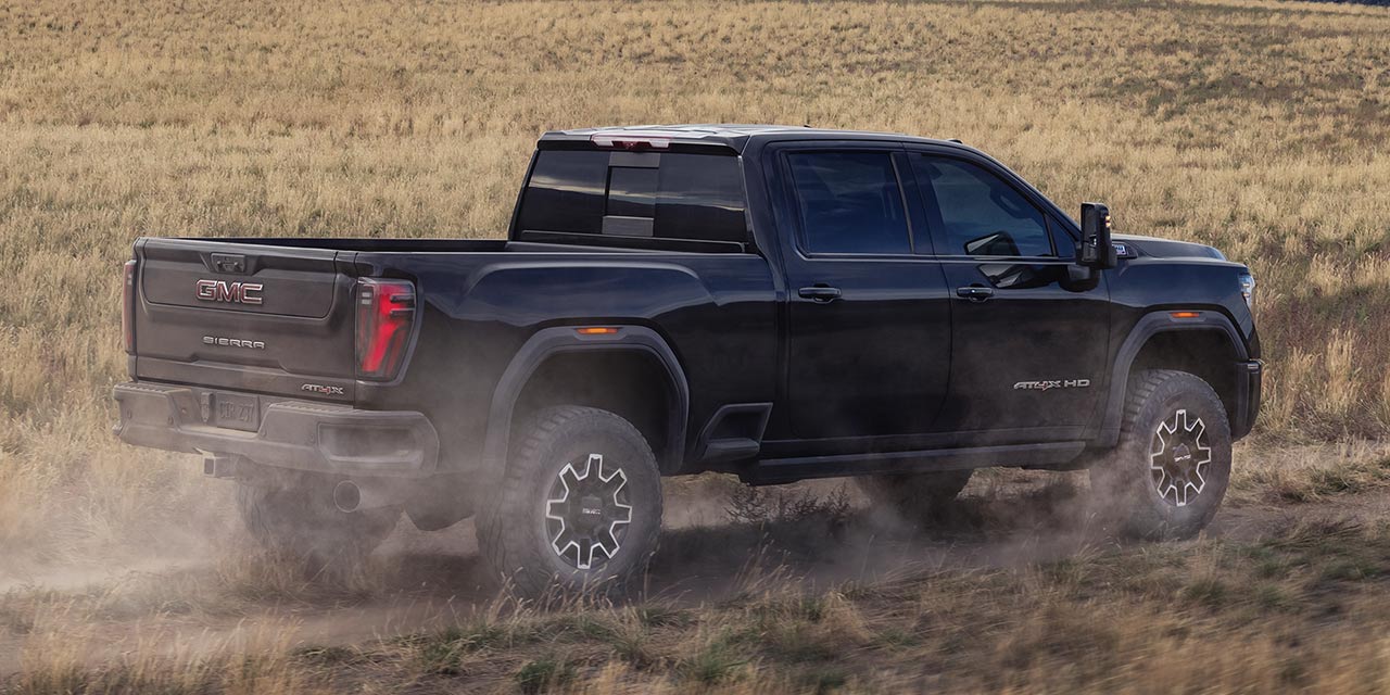 Rear Three-quarter View of a Black 2026 GMC Sierra HD Heavy Duty Off-Road Truck and Kicking Up Dirt