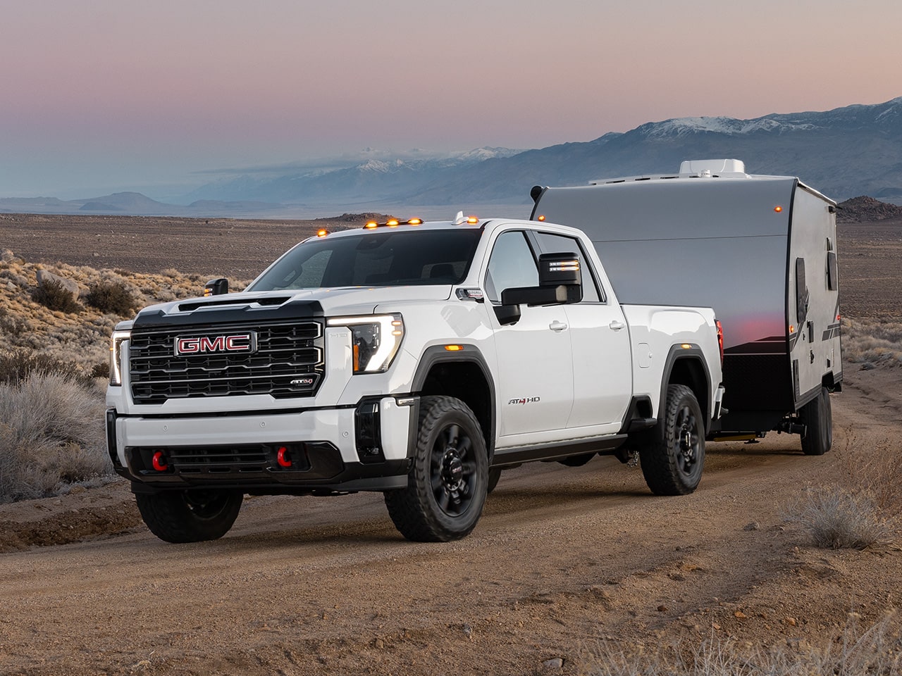 A 2026 GMC Sierra HD AT4 Truck Hauling a Trailer Through the Desert at Dusk