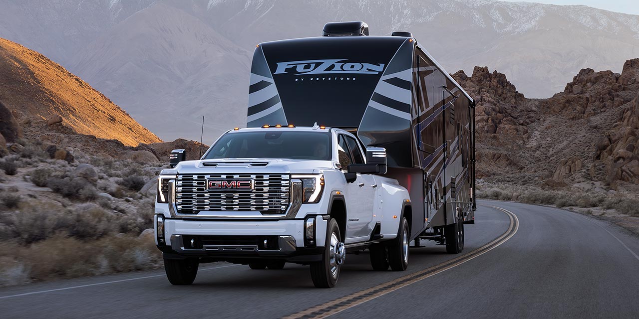 A 2026 GMC Sierra HD Denali Truck Hauling a RV Through the Mountains at Dusk
