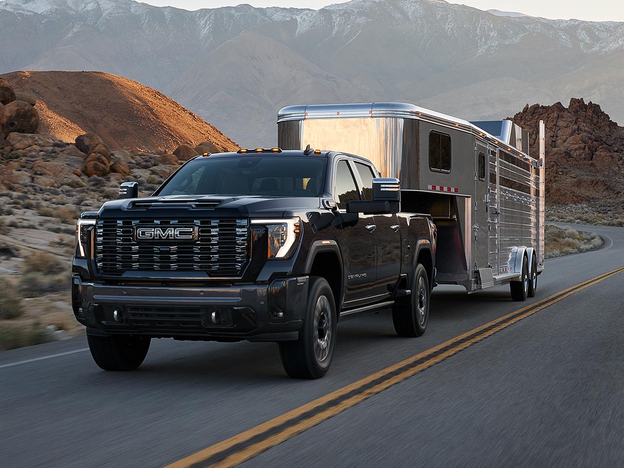 A 2026 GMC Sierra HD Denali Luxury Truck Hauling a Trailer Through the Mountains at Dusk