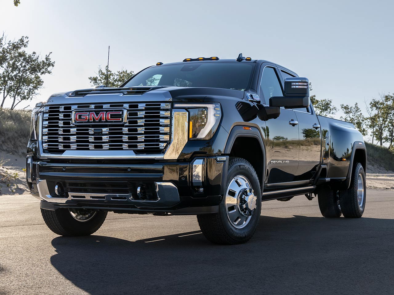 Wide Front Three-Quarters View of a 2026 GMC Sierra HD Denali Luxury Truck Driving on an Open Road