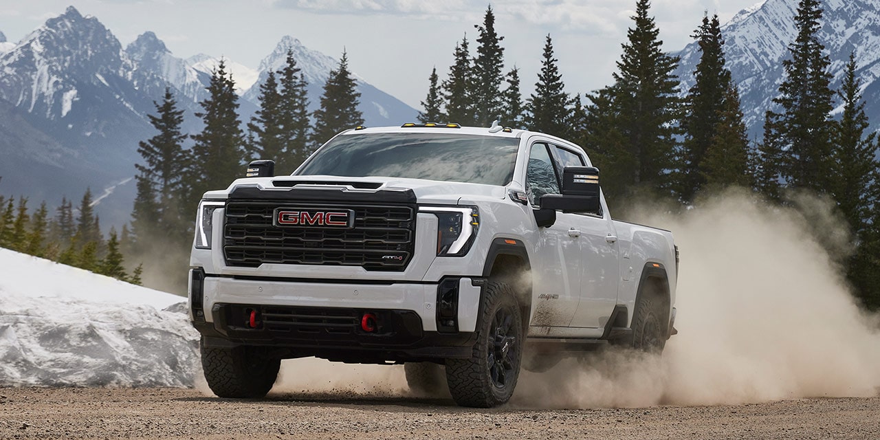 Front View of the 2026 GMC Sierra HD Heavy Duty Truck Driving Out of a Forest