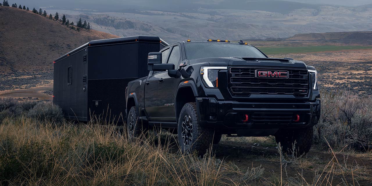 The 2026 GMC Sierra HD Heavy Duty Truck Pulling a Trailer Through a Terrain Back Road