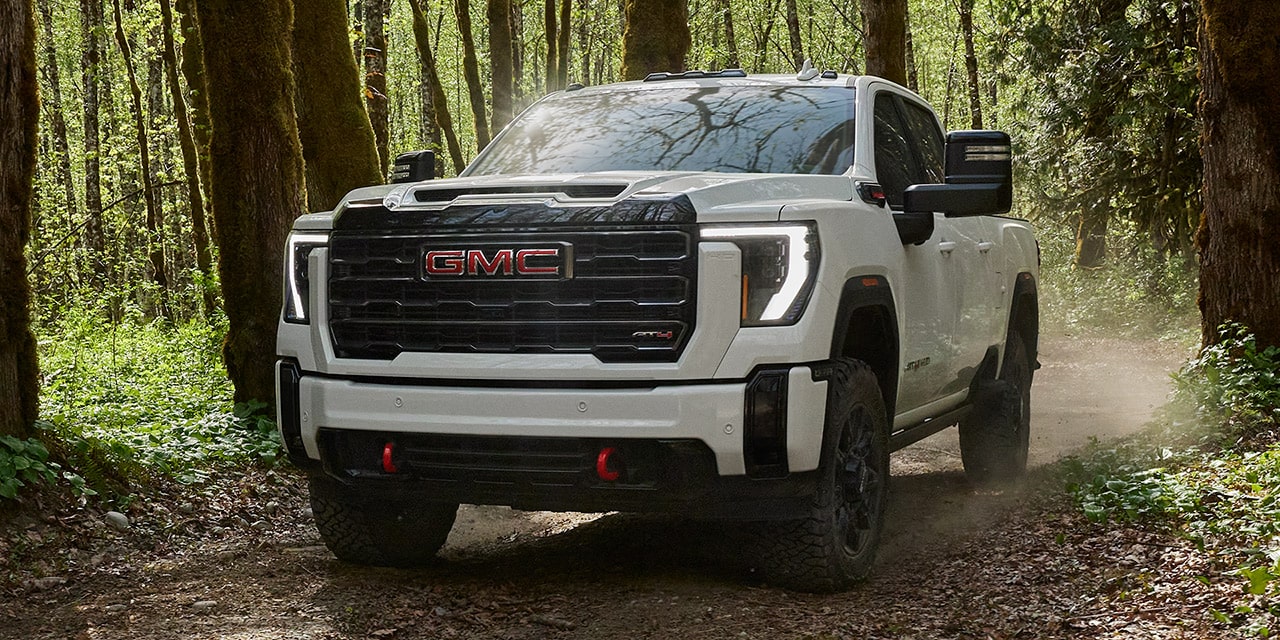 Front View of the 2026 GMC Sierra HD Heavy Duty Truck Driving Through a Green Forest