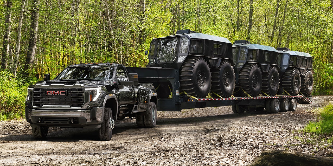 the 2026 GMC Sierra HD Heavy Duty Truck Pulling a Large Piece of Equipment on a Dirt Road