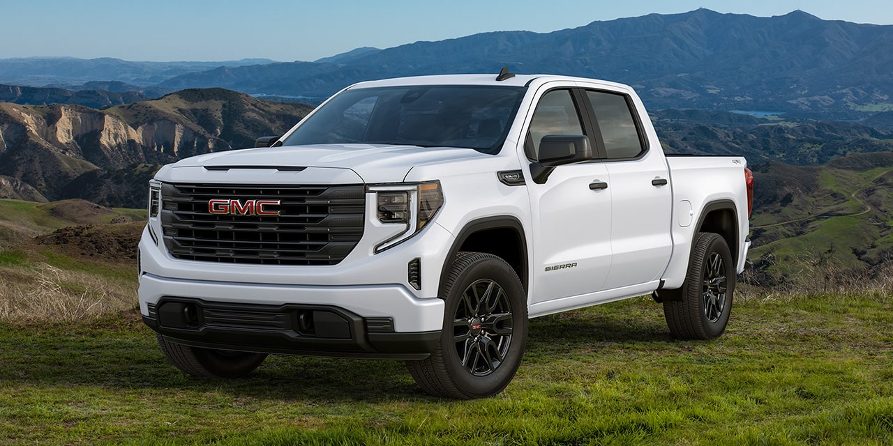 Front Three-Quarters View of a White 2026 GMC Sierra 1500 Pickup Truck Parked in a Green Valley