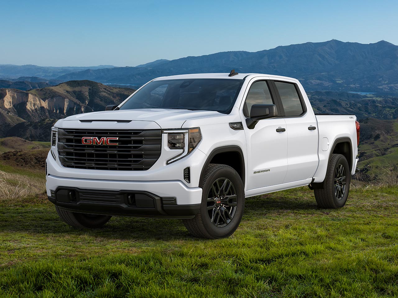 Front Three-Quarters View of a White 2026 GMC Sierra 1500 Pickup Truck Parked in a Green Valley
