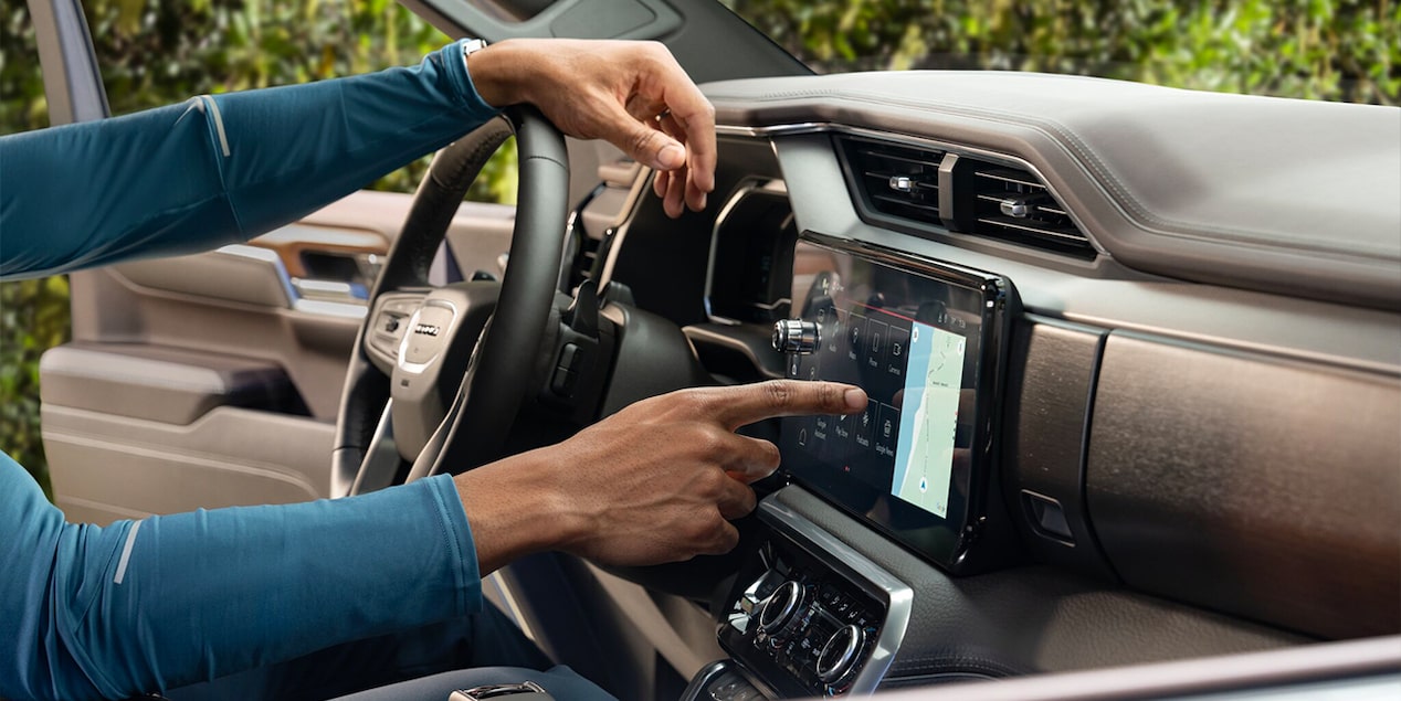 Close-up View of a Driver Pressing a Control on the Infotainment System in his GMC Vehicle
