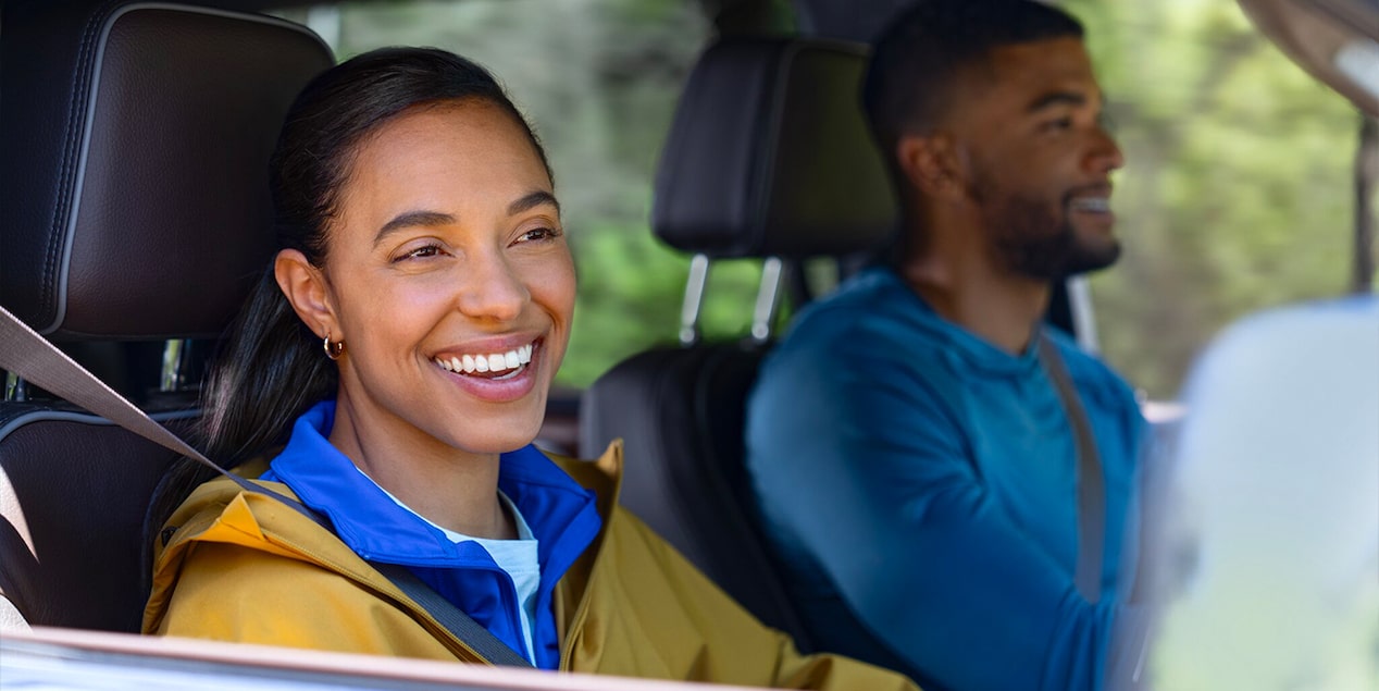 Couple Smiling and Driving in Their GMC Vehicle