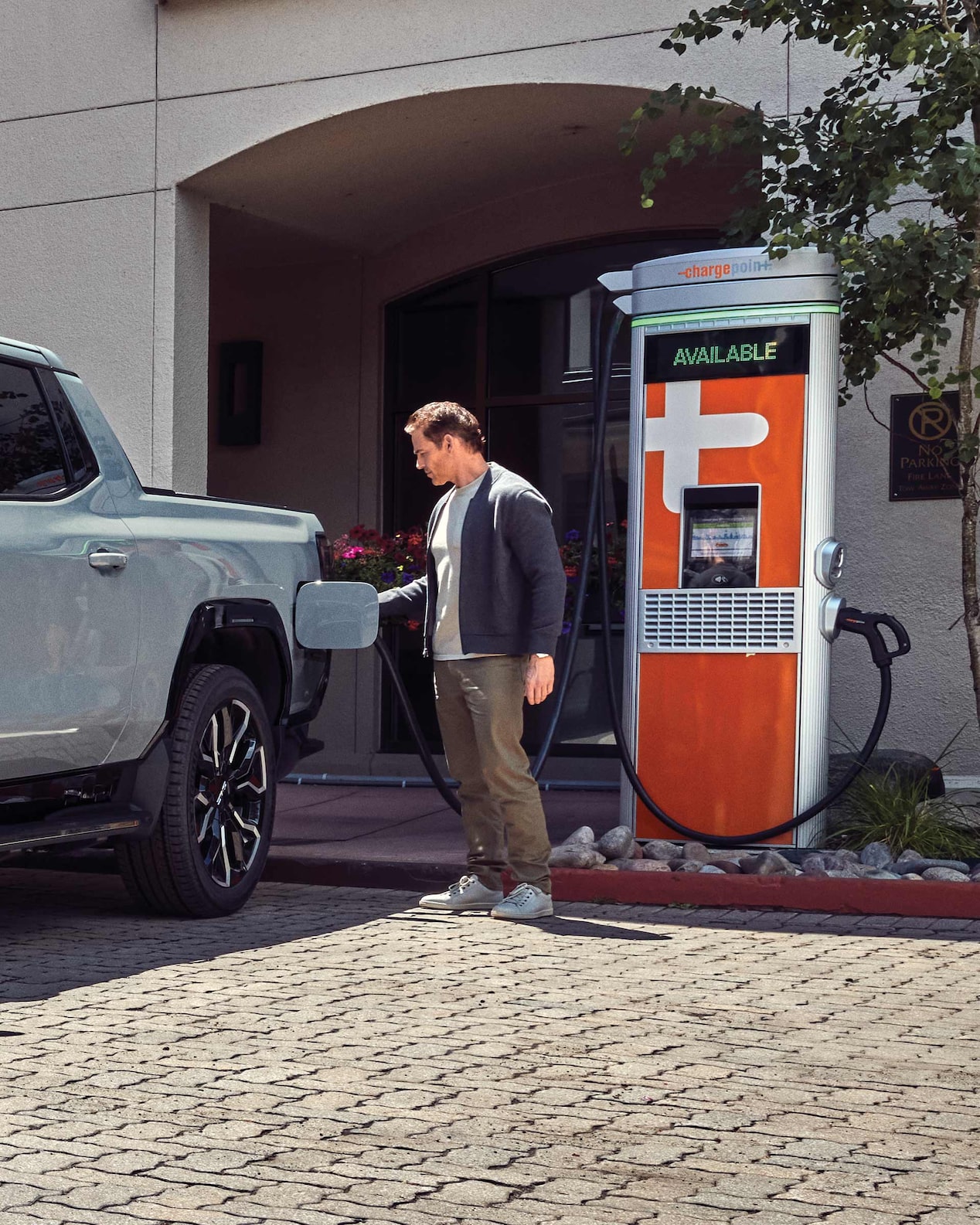 A Man Charging His GMC Electric Vehicle at a Public Charging Station